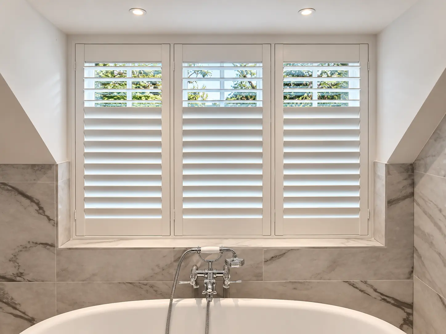 Full-height bathroom shutters above the bath in the Esher display house.