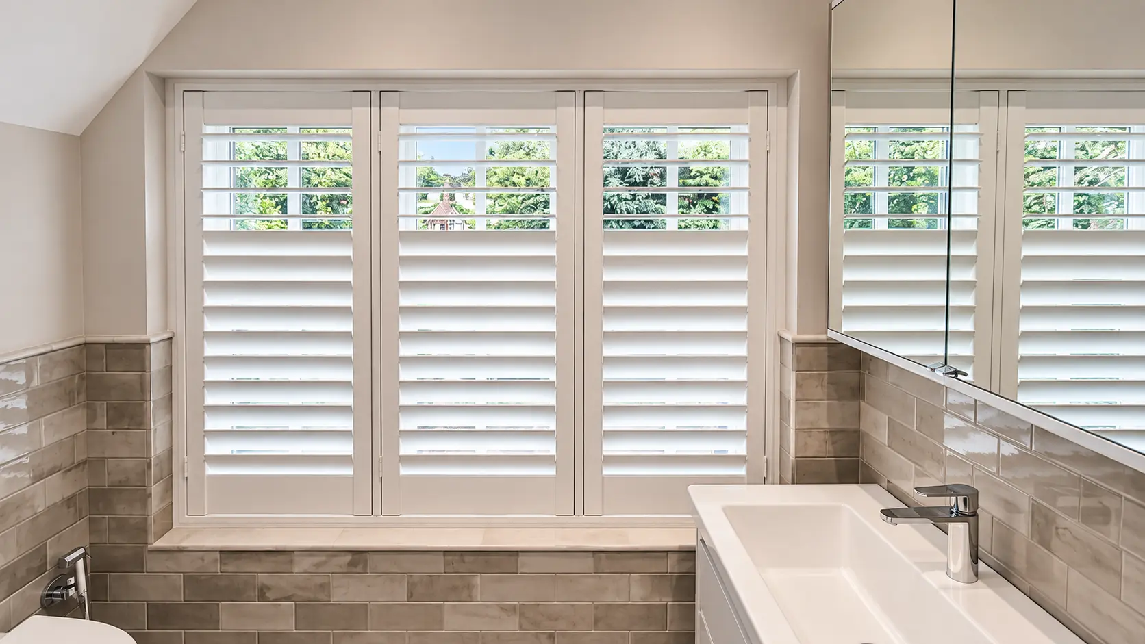 Full-height bathroom shutters beside the basin in the Esher display house.