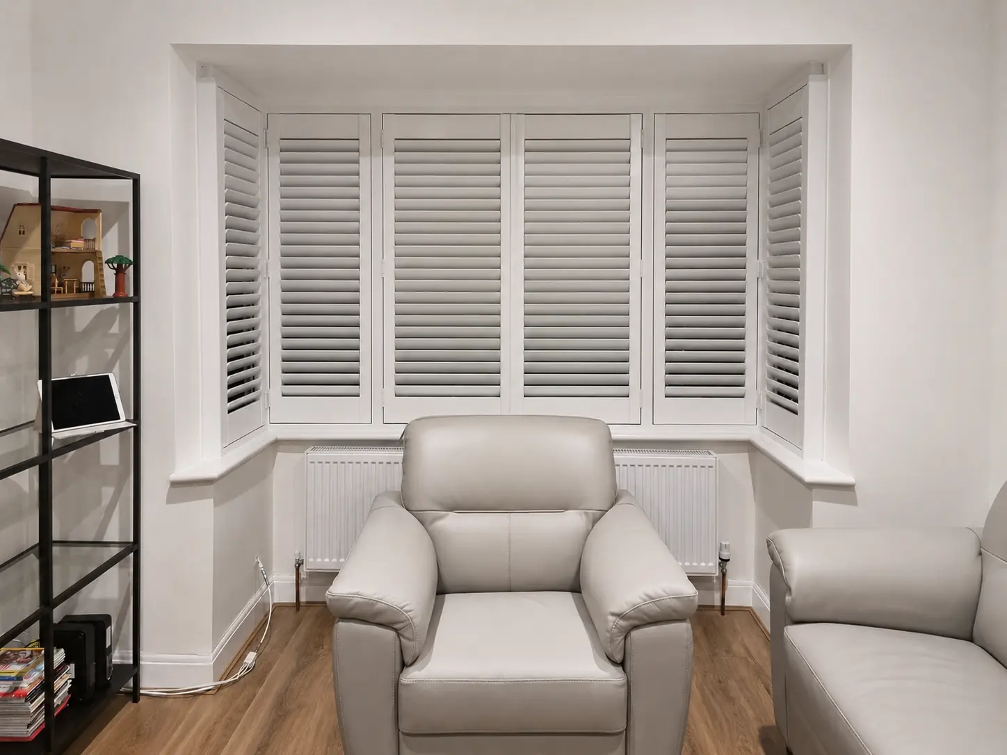 Full-height plantation shutters fitted in a Surbiton living-room bay window.