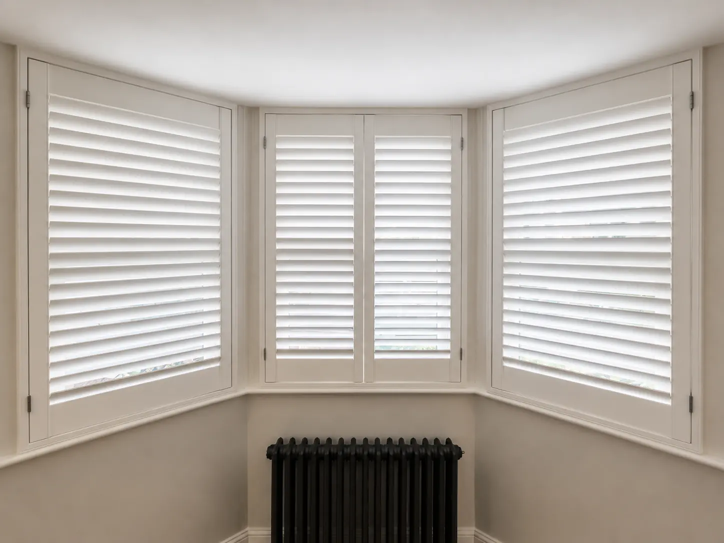 Full-height plantation shutters fitted in a Teddington living-room bay window.