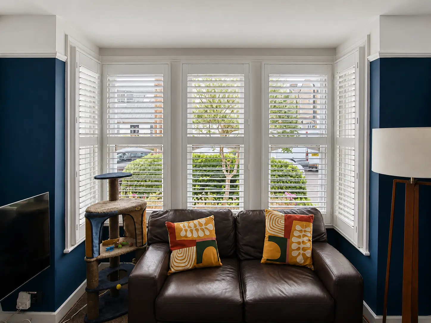 Full-height plantation shutters fitted in a Twickenham living-room bay window.